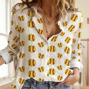 Könnte beinhalten: Weißes Button-Down-Hemd mit einem sich wiederholenden Muster aus gelben Softbällen und herzförmigen Softbällen. Die Softbälle haben rote Nähte. Das langärmlige Hemd ist aus leichtem Stoff gefertigt.