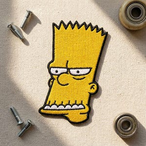 May include: Embroidered yellow patch featuring Bart Simpson with black outline and details. The patch is on a beige fabric surface, with three silver screws and two small wheels.