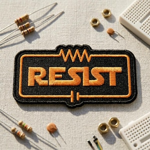 May include: Black embroidered patch with the word "RESIST" in orange, surrounded by an orange border. The patch is rectangular with a wavy line design at the top. Various electronic components, including resistors and nuts, are scattered around the patch.