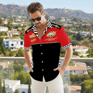 May include: A short-sleeved button-down shirt featuring a red and black color block design. The top portion is red with "95 Lightning McQueen" graphics, while the bottom is black. The collar and sleeve cuffs have a checkered pattern.