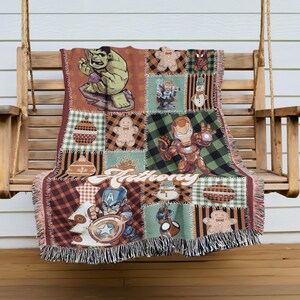 A colorful throw blanket featuring various cartoon characters, including the Hulk, Iron Man, and other popular superheroes, is hanging on a wooden bench.