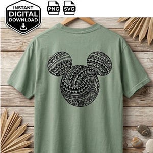 Könnte beinhalten: Ein salbeigrünes Kurzarm-T-Shirt mit einer großen schwarzen Grafik auf der Rückseite. Die Grafik zeigt eine stilisierte Maus-Kopf-Silhouette, die mit komplexen schwarzen, tribal-inspirierten geometrischen Mustern und kleinen Meeresschildkröten gefüllt ist.
