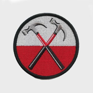 May include: Embroidered patch featuring a circular design with a black border. The patch has a white and red background with two crossed hammers in the center. The hammers are gray with red and black handles.