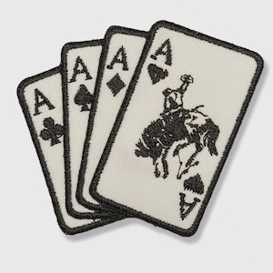 May include: Three playing card patches featuring the Ace of Clubs, Diamonds, and Spades, and a cowboy riding a bucking bronco. Each card has a black embroidered border and design on a cream background.