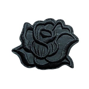 May include: Black embroidered rose patch. The patch features a detailed design of a rose flower with textured petals and leaves. The patch is likely for decorative purposes, such as adding to clothing or accessories.