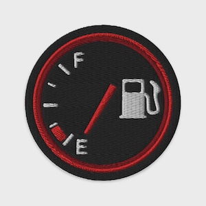 May include: A circular embroidered patch featuring a black fuel gauge design with a red border. The gauge includes white tick marks, the letters F and E, a red needle pointing toward the empty mark, and a white icon of a fuel pump nozzle.