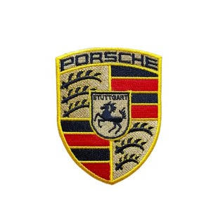 May include: Embroidered patch featuring the Porsche crest. The crest is shield-shaped with a gold border and a black horse in the center. The word "PORSCHE" is arched across the top in gold, with "STUTTGART" below the horse.