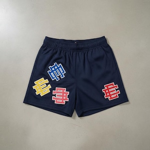 May include: Navy blue mesh shorts with a drawstring waistband. The shorts feature four colorful embroidered patches with a stylized "E" design in yellow, red, and blue. The shorts are a casual athletic style.