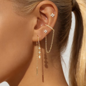 Pendientes de circonita chapados en oro con forma de trébol de cuatro hojas y cadena tipo brazalete.