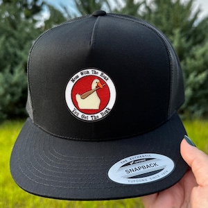May include: Black Snapback hat with a mesh back and a flat brim. The hat features a circular patch with a cartoon duck holding a baseball bat, with the text "Mess With The Honk, You Get The Bonk". The hat has a Yupoong Snapback label.