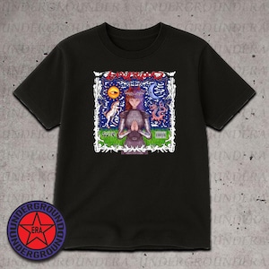 May include: Black t-shirt featuring a colorful graphic design. The design includes the text "Loveblood" in red, a figure with hands clasped in prayer, and various celestial and mythical elements. The shirt has short sleeves and a crew neck.