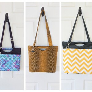 May include: Three different tote bags hanging on hooks. The bag on the left has a blue and purple mermaid scale pattern. The middle bag is brown with a snakeskin pattern. The bag on the right has a black and yellow chevron pattern.