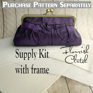 May include: A purple fabric clutch purse with a gold metal frame and a white fabric supply kit with the text "Supply Kit with frame + flourish clutch" printed on it.