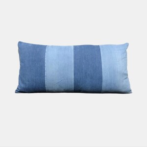 May include: A rectangular cushion with a denim design. The cushion features vertical stripes in varying shades of blue denim. The cushion is approximately 61 cm long and 30 cm wide.