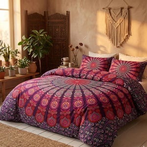 Puede incluir: Juego de funda nórdica y fundas de almohada con estampado de mandala morado y rojo. La ropa de cama presenta un diseño simétrico detallado con un motivo central de sol y un borde floral, creando una estética bohemia.