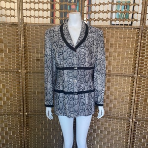 May include: A grey and black snakeskin patterned blazer with a black trim and silver buttons.