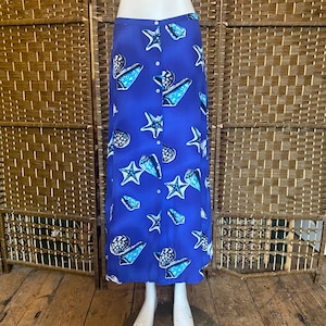 May include: A long blue skirt with a button-up front and a seashell and starfish print.