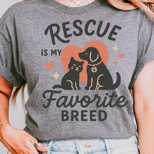 May include: Grey t-shirt featuring the text "Rescue is my Favorite Breed" with a black cat and dog graphic inside a heart. Digital download only.