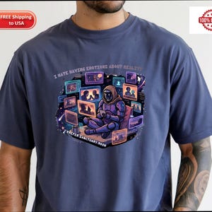 May include: Navy blue t-shirt with a colorful graphic of a figure in a futuristic suit surrounded by screens. The text on the shirt reads "I HATE HAVING EMOTIONS ABOUT REALITY" and "I PREFER SANCTUARY MOON". Made of 100% cotton.