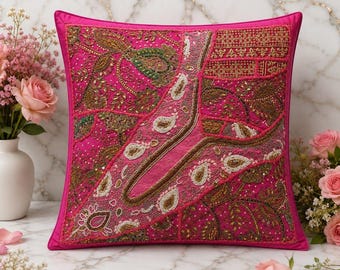 Puede incluir: Un cojín cuadrado de color rosa fucsia vibrante, con intrincados bordados hechos a mano, hilo metálico dorado y cuentas blancas en un patrón de cachemira y parches geométricos, con un borde de tela rosa fucsia a juego.