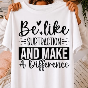 May include: A white short-sleeved t-shirt featuring black text that reads Be like subtraction and make a difference. The design includes a small heart and flower icon above the word subtraction, with the words and make a difference below.