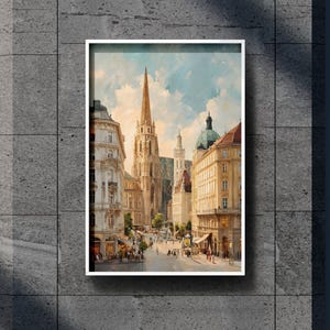 May include: Framed watercolour painting of a European city street scene. The artwork depicts a tall church with a spire, surrounded by buildings with shops and people walking. The sky is blue with clouds.