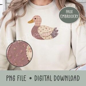 May include: A beige crewneck sweatshirt featuring a central graphic of a duck composed of various patterned fabric patches, including a pink gingham head and floral wing. A circular inset shows a close-up of the mauve floral fabric texture.