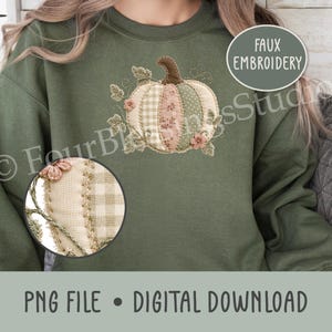 Op de afbeelding: Een olijfgroen sweatshirt met een faux borduurontwerp van een pompoen met patchwork-stijl segmenten in crème, roze en groene patronen, geaccentueerd met kleine bloemmotieven en rankdetails, inclusief een cirkelvormige close-up.