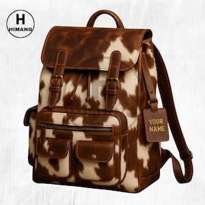 May include: A brown and white cowhide-patterned backpack with a flap closure, two front pockets, and a top handle. The bag features brown leather accents, adjustable straps, and a tag that says "YOUR NAME".