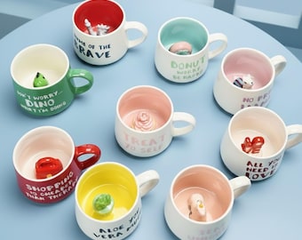 Taza de cerámica con figura oculta en el fondo: un adorable animal u objeto sorpresa en su interior. Ideal como regalo original o para decorar tu escritorio.