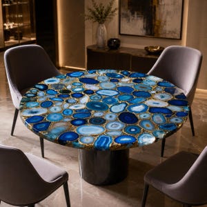 May include: A round dining table featuring a tabletop composed of numerous polished blue agate slices with gold-toned edges, supported by a solid black cylindrical pedestal base, surrounded by four grey upholstered chairs.