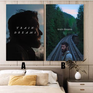 May include: Two framed art prints. One features a silhouette of a man with the text "TRAIN DREAMS". The other shows a man standing on train tracks with the text "train dreams". The prints are displayed above a bed.