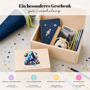 Peut inclure: Une bo&icirc;te en bois ouverte contenant des fournitures scolaires, dont un cahier avec un motif de fus&eacute;e et une trousse. Le texte sur la bo&icirc;te dit "BEREIT F&Uuml;R NEUE ABENTEUER".