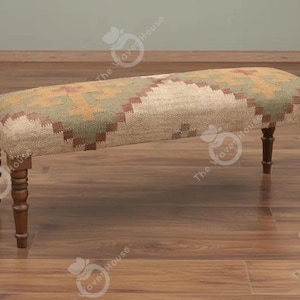 May include: A rectangular bench featuring a woven textile top with a geometric pattern in shades of beige, sage green, and brown. The seat is supported by four dark brown wooden legs with a turned, spindle-style design and a smooth finish.
