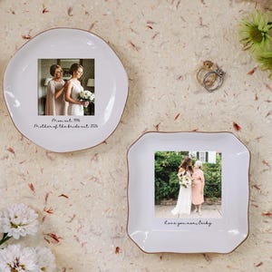 Op de afbeelding: Twee witte keramische schalen met een gouden rand, elk met een foto. Eén schaal is rond, de andere vierkant. De ronde schaal heeft de tekst "Moment 1996 Mother of the bride out 2026". De vierkante schaal heeft de tekst "Love you mom, Becky".