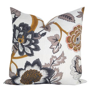 May include: A white pillow with a floral pattern in shades of gray, brown, and gold. The flowers are stylized and have a vintage feel.