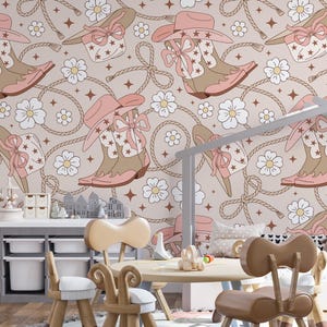 May include: A whimsical nursery scene featuring a repeating pattern of cowboy boots, hats, and floral elements in soft pink and tan hues. The wallpaper design includes rope and star accents, creating a playful, country-inspired aesthetic.