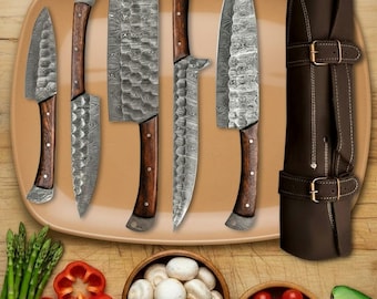 May include: A set of six Damascus steel kitchen knives with wooden handles, displayed on a brown platter. The knives vary in size and shape, including a cleaver and a chef's knife. A brown leather knife sheath is also included.