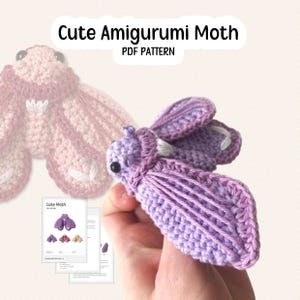 Puede incluir: Una polilla amigurumi de ganchillo morada con detalles blancos y ojos negros. La imagen incluye el texto "Cute Amigurumi Moth PDF Pattern" y una hoja de patrones que muestra diferentes variaciones de color.