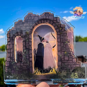 May include: A clear acrylic standee featuring a detailed illustration of two figures standing within a stone archway ruin. One figure wears a dark blue robe and pointed hat, while the other wears a light cloak. The text IM JASS ART is visible.