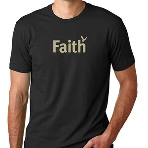Peut inclure: T-shirt noir avec un graphique beige d'un oiseau et le mot "Faith".