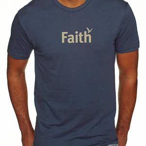 Peut inclure: Un t-shirt bleu marine avec le mot "Faith" imprim&eacute; en beige avec un petit oiseau graphique au-dessus du mot.