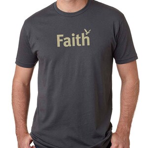 Peut inclure: Un t-shirt gris anthracite avec un motif beige repr&eacute;sentant le mot "Faith" et un petit oiseau.