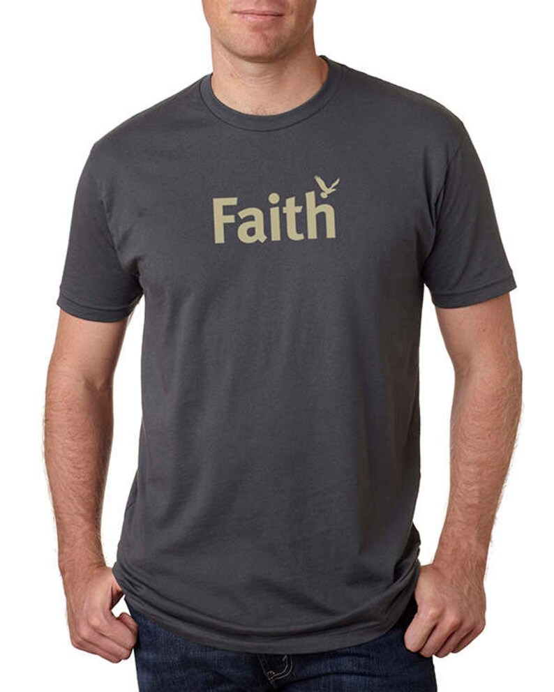 Peut inclure: Un t-shirt gris anthracite avec un motif beige repr&eacute;sentant le mot "Faith" et un petit oiseau.