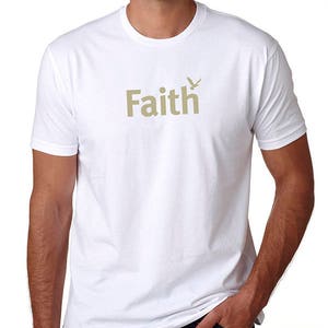 Peut inclure: T-shirt blanc avec un graphisme beige du mot "Faith" et un petit motif d'oiseau.