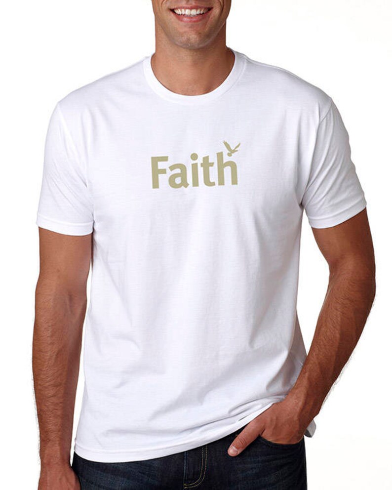 Peut inclure: T-shirt blanc avec un graphisme beige du mot "Faith" et un petit motif d'oiseau.