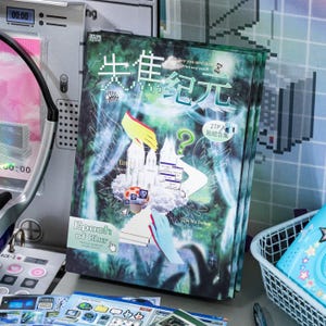 Puede incluir: Un libro de pegatinas rectangular con un fondo verde oscuro etéreo que presenta arte digital, texto pixelado e imágenes surrealistas. La portada muestra los caracteres chinos 失焦纪元, el texto en inglés Epoch of Blur y varios iconos informáticos.