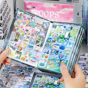 Könnte beinhalten: Ein Stickerbuch mit zwei aufgeschlagenen Seiten, die mit einer Vielzahl kleiner, bunter Aufkleber gefüllt sind. Die Motive umfassen Miniatur-Computerfenster, Zeichentricktiere, Sterne, Herzen und verschiedene Objekte in einer bunten Optik.