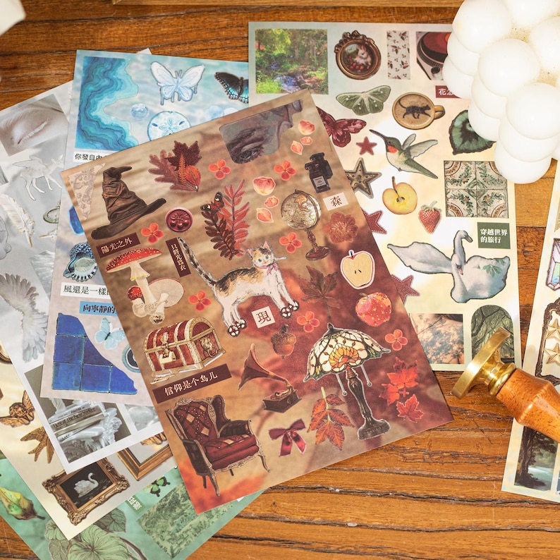 May include: A collection of decorative stickers with various designs, including a cat, a treasure chest, a stained glass lamp, and butterflies. The stickers have a vintage aesthetic with warm, earthy tones and some text.