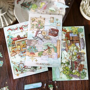 May include: A collection of decorative paper sheets and stickers with a travel theme. The sheets feature watercolor illustrations of maps, trees, and vintage luggage. The text "TRAVELFAR" is visible on one sheet. The color palette includes greens, browns, and blues.